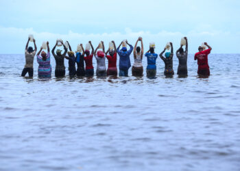 Hombres y mujeres en el mar, elevando sus cántaros al cielo. Imagen de Aquiles Mensa Sité