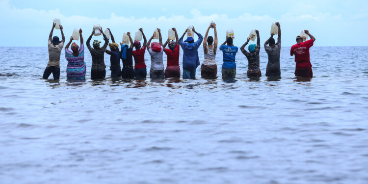 Hombres y mujeres en el mar, elevando sus cántaros al cielo. Imagen de Aquiles Mensa Sité